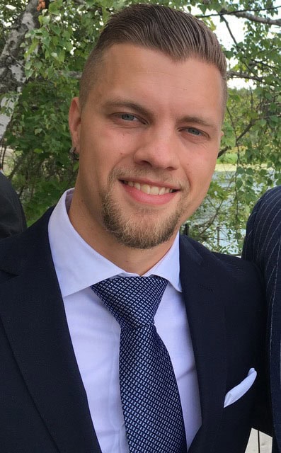 Ung man i kostym med leende, utomhus, professionell bild.