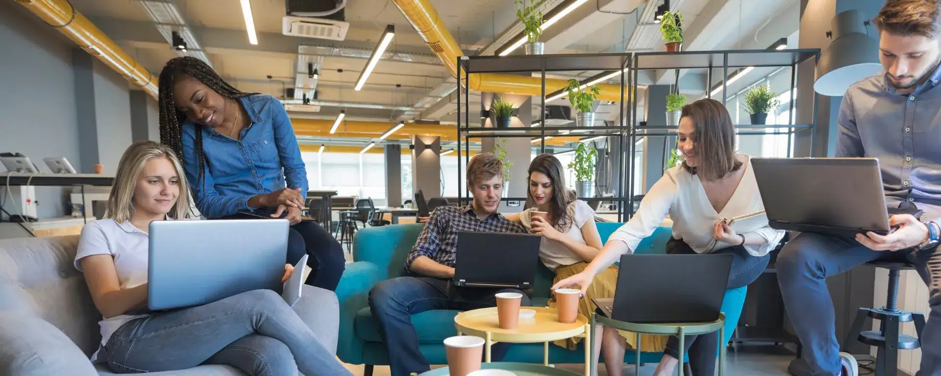 Grupp unga ingenj&ouml;rer i ett modernt kontorslandskap med laptops.